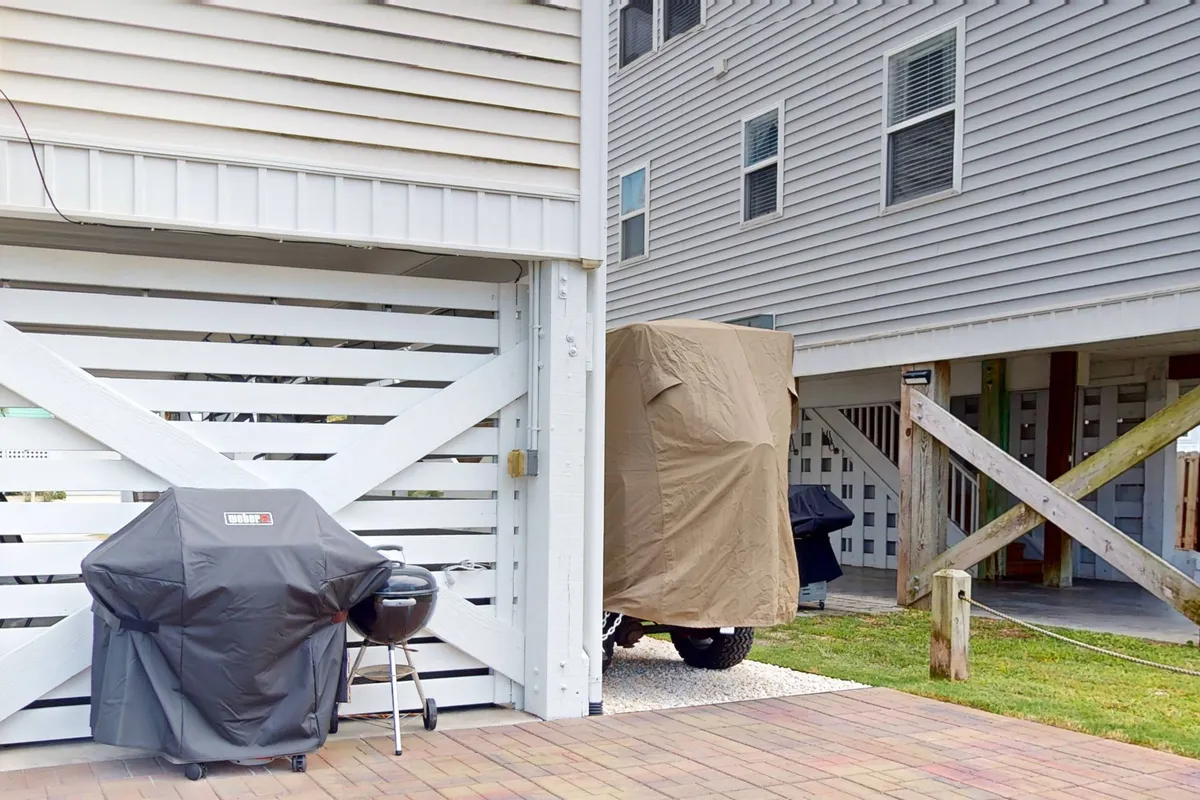 This image features a private ground-level patio area with a gas grill, a covered vehicle, and a wooden structure. The presence of the grill and open space makes it an ideal setting for outdoor cooking and group gatherings, as referenced in the section's emphasis on cookouts and private patios for guests.